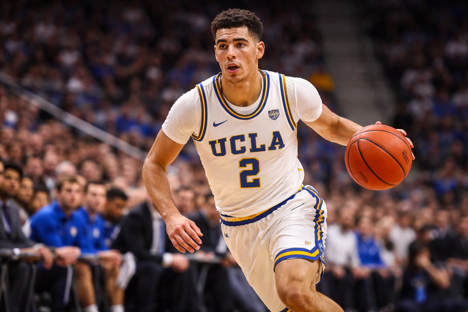 Lonzo Ball mengenakan jersey UCLA putih dengan aksen biru dan emas, menggiring bola basket di tengah pertandingan NCAA 2017. Fokusnya terlihat saat menembus pertahanan lawan, dengan rekan satu tim dan penonton kabur di latar belakang, menampilkan atmosfer stadion yang penuh semangat.